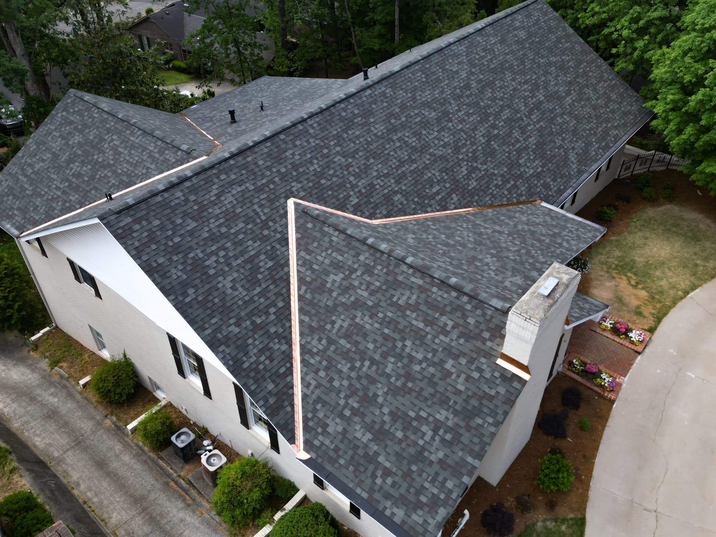 Aerial view of a finished residential shingle roof with copper valleys